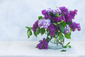 Bunch of fresh lilac flowers in vase on gray background background