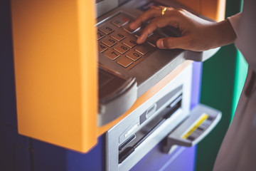 Close up of hand entering pin code at atm machine to withdraw money.finance concept.