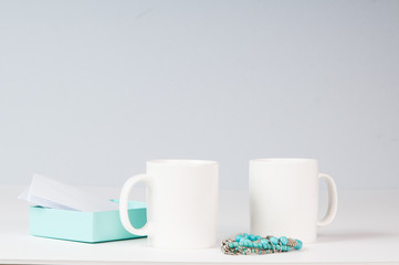 mockup of two white coffee mugs in a simple setting