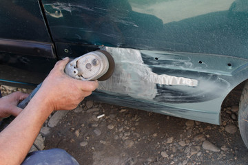 mechanic worker repairman sanding polishing car body and preparing automobile for painting during...