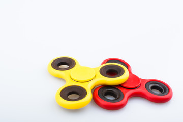 Red and yellow fidget finger spinner stress anxiety relief toy isolated on white background.