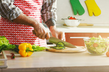 male hands cutting cucumber with knife