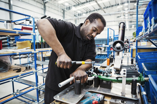 Male skilled factory worker, a man holding a tool, working to assemble parts of a bicycle in a factory. 