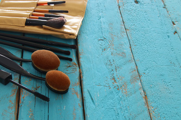 Set of professional makeup brushes on wooden table