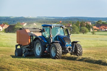 Blue tractor on the pasture.. Agricultural work on the farm in the Czech Republic.