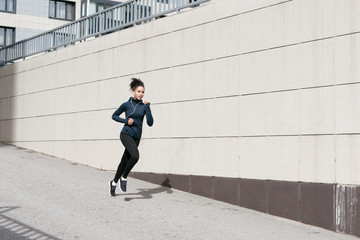 Mixed race woman wearing sports clothes, running on city street