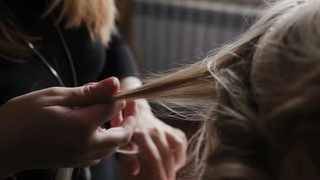 A woman does the hairstyle of another woman, smoothes her hair with her hands