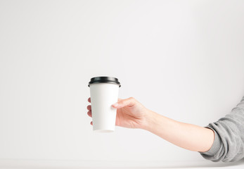 woman's hand holding a white takeout coffee cup