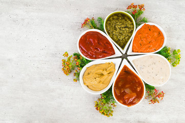 A set of sauces in a form of flower on a light gray stone background.