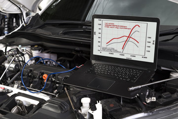 Professional car mechanic working in auto repair service by system computer