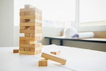 Planning risk and strategy in construction site or office. Engineering gambling placing wooden block on a tower.