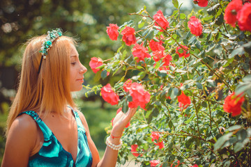 Young blonde cute american woman on a walk outside the city by the river and garden in a colored sarafan in romantic style