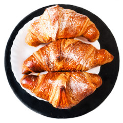 Fresh croissants on a plate isolated on white background  close up. Tasty golden croissants  macro