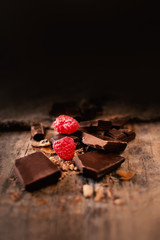 Broken chocolate bar with red ripe  raspberries on dark brown  background close up, macro © nataliazakharova