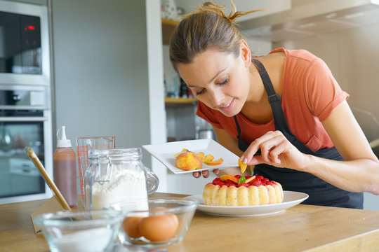 Young Woman In Domestic Kitchen Baking Raspberry Cake