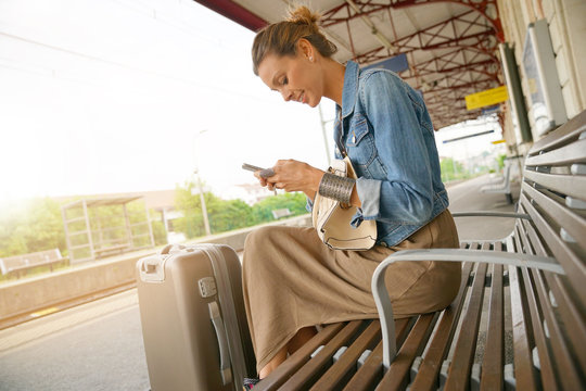 Young woman using smartphone while waiting for the train