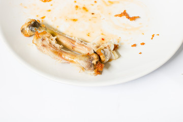 close up of chicken  bone on the white dish with with waste food  isolate background , waste food , chicken bone isolated white , copy space , spoon