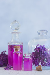 Obraz na płótnie Canvas Lilac essence in glass vials and fresh lilac flowers on gray background