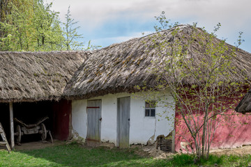 National Museum Pirogovo in the outdoors near Kiev. Ancient peasant Ukrainian house with a thatched roof, spring landscape in the old village of national architecture, Ukraine.