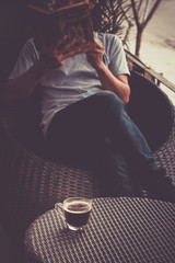 Fototapeta na wymiar A man reading a book with drinking coffee