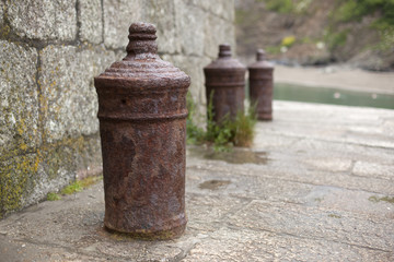 Old rusty mooring posts at Polkerris harbour, Cornwall
