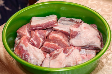 Raw chopped meat on bones in a green bowl