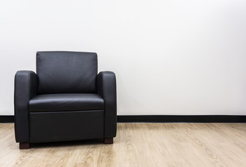 Single Black leather armchair in living room with wooden floor.