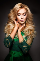 Fototapeta premium Portrait of elegant sexy blonde woman with long curly hair and glamour makeup. Lady looking at camera.