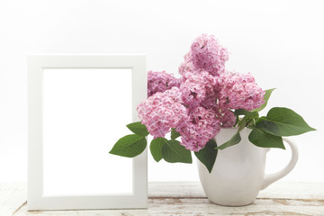 Bunch lilac in vase on wooden table and white frame mock up