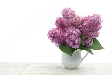 Bunch lilac in vase on wooden table