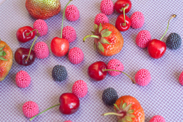 A group of strawberries, cherries and candies raspberry isolated  on the violet background