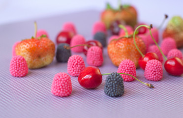 A group of strawberries, cherries and candies raspberry isolated  on the violet background
