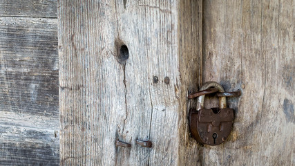 Natural material. Old metal rusty padlock, bolt on a wooden door. Old wooden brown background close-up.