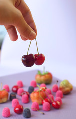 Girl hand holding cherry on the blurred colored background