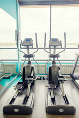 Modern gym interior with equipment. Fitness club with row of treadmills for fitness cardio training in evening backlight. Healthy lifestyle concept