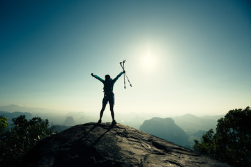 cheering successful woman hiker open arms on sunrise mountain top