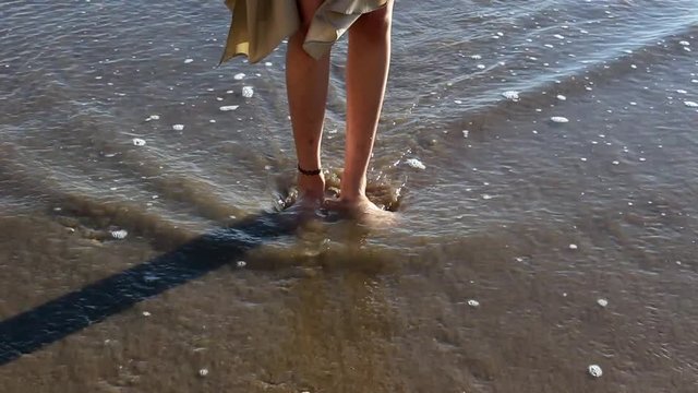 Beautiful woman legs with choker washing by sea on the beach