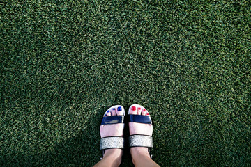 Female feet on green grass in the park