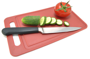 Огурец помидор и нож на разделочной доске 