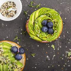 Round buns for breakfast with avocado in the form of a rose with a sauce of yogurt with a variety of sesame seedsAgainst a dark background . Top view. The concept of healthy nutrition
