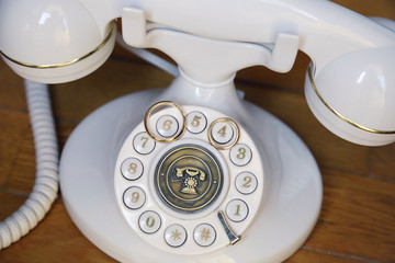 Anelli d'oro sopra un telefono molto antico di color bianco