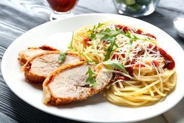 Tasty pasta with chicken parmesan slices and herbs on plate
