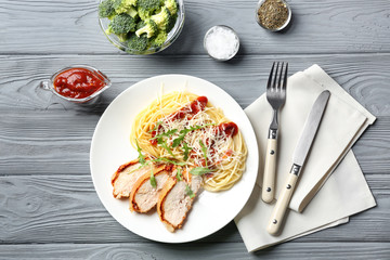 Tasty pasta with chicken parmesan slices and herbs on plate