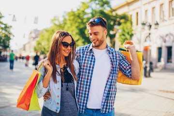 Happy young couple walking in the city after shopping
