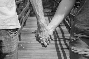 Man and woman holding hands with a wooden bridge in the background