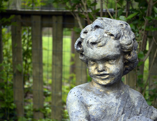 Stone cherub statue in garden 