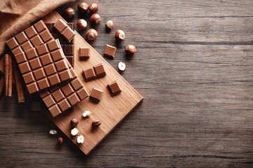 Chocolate bars with nuts on wooden background