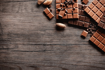 Chocolate bars with coffee beans on wooden background