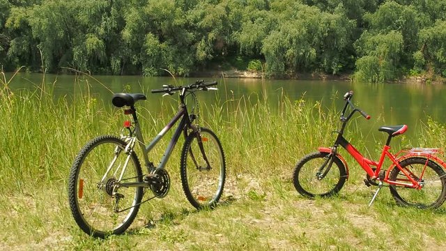 Two bicycles by the river. Children's and adult bicycles on vacation.