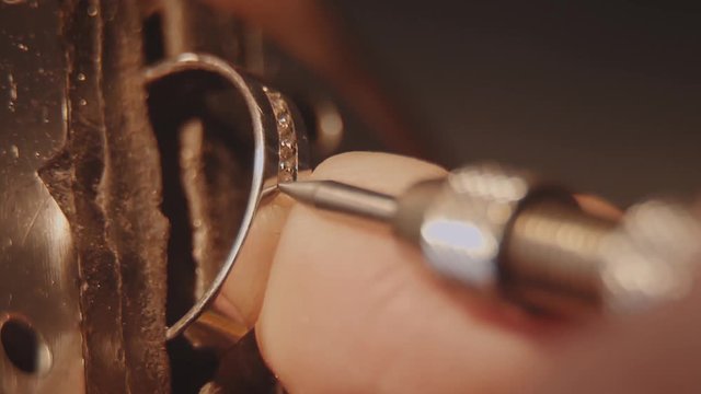 The jeweller is setting a precious stone. Craft jewelery making. Ring repairing. Putting the diamond on the ring. Macro video. Craft jewelery making with professional tools. Putting the diamond on the